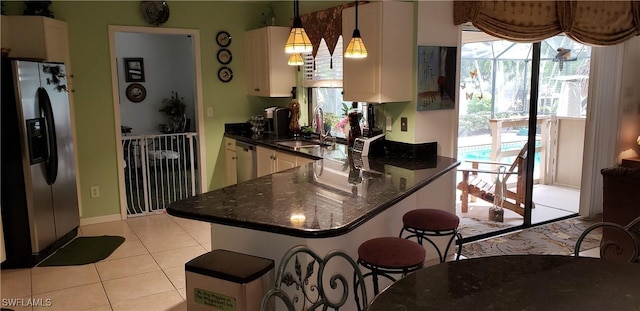 kitchen with kitchen peninsula, appliances with stainless steel finishes, sink, light tile patterned floors, and pendant lighting