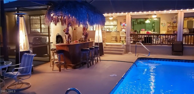 view of swimming pool featuring a patio and an outdoor bar