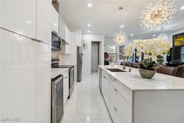 kitchen with a notable chandelier, sink, hanging light fixtures, stainless steel appliances, and white cabinets