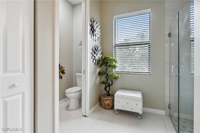 bathroom featuring toilet, tile patterned floors, and a shower with shower door