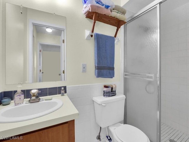 bathroom featuring vanity, a shower with shower door, tile walls, and toilet