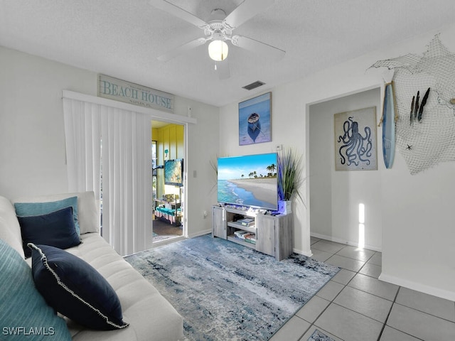 tiled living room featuring ceiling fan and a textured ceiling