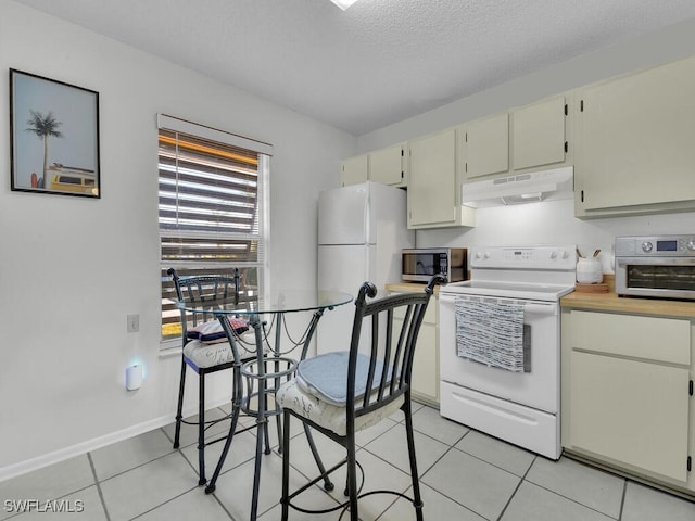 kitchen with white appliances, cream cabinets, a textured ceiling, and light tile patterned floors