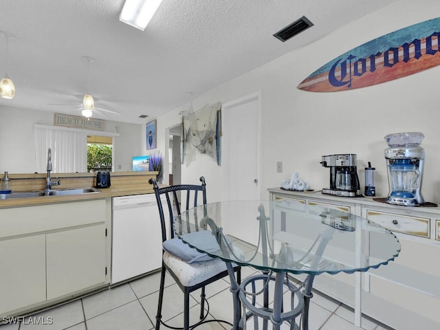 kitchen featuring dishwasher, sink, light tile patterned floors, and white cabinets