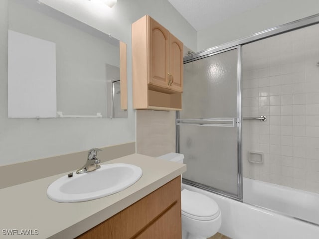 full bathroom featuring vanity, enclosed tub / shower combo, and toilet