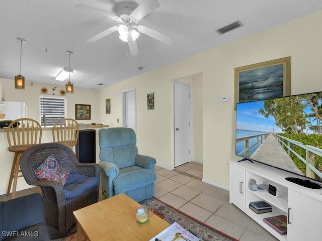 living room with ceiling fan, a textured ceiling, and light tile patterned flooring