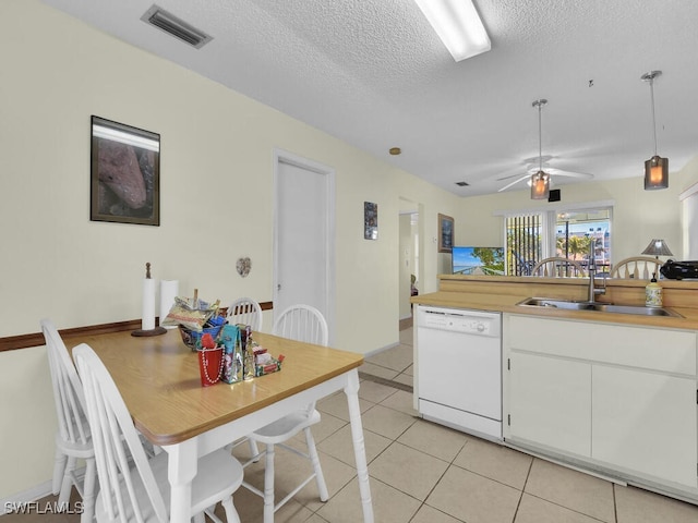 kitchen featuring sink, light tile patterned floors, dishwasher, white cabinetry, and a textured ceiling