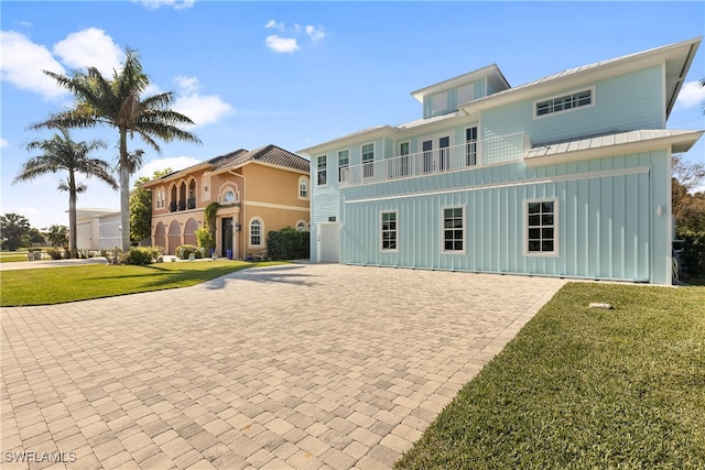 view of front of home with a front yard, a balcony, and a garage