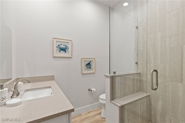 bathroom featuring hardwood / wood-style floors, vanity, toilet, and walk in shower