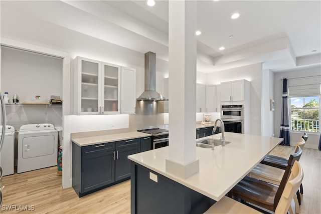 kitchen with white cabinets, sink, wall chimney exhaust hood, independent washer and dryer, and stainless steel appliances