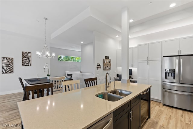 kitchen featuring light stone countertops, stainless steel appliances, sink, decorative light fixtures, and white cabinets