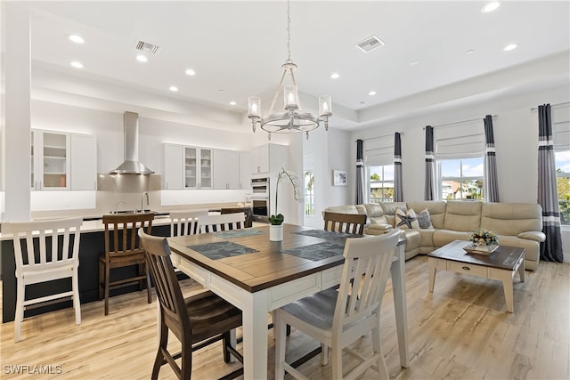 dining area featuring sink, light hardwood / wood-style flooring, and a notable chandelier