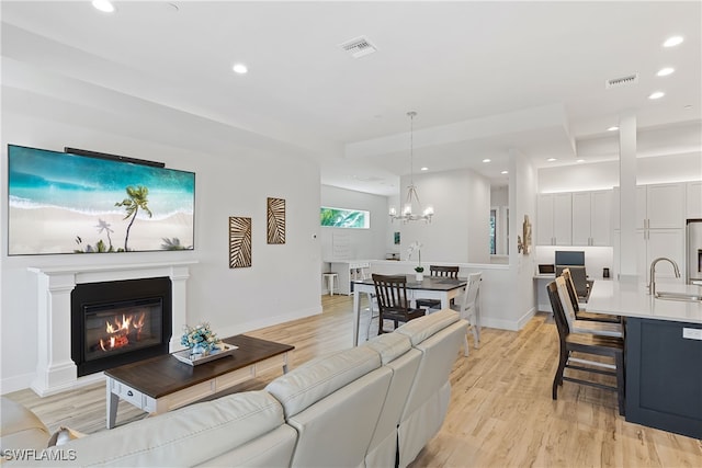 3967 Skyway Dr Unit 14, Naples, FL 34112 - living room with baseboards, light wood-style floors, a chandelier, recessed lighting, and a glass covered fireplace