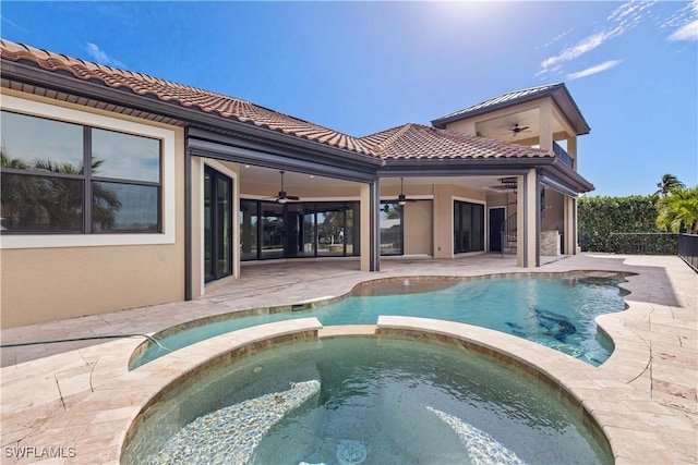 rear view of house featuring a patio, ceiling fan, and a pool with hot tub