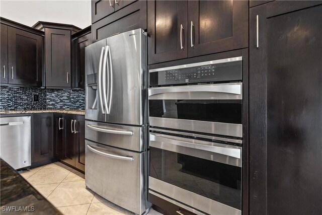 kitchen featuring decorative backsplash, light stone counters, dark brown cabinets, stainless steel appliances, and light tile patterned floors