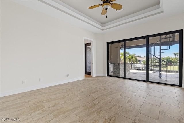 spare room with ceiling fan and a tray ceiling