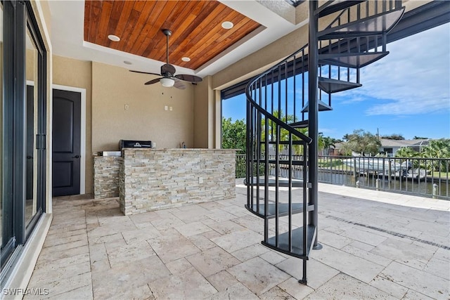 view of patio featuring a water view, ceiling fan, and exterior kitchen