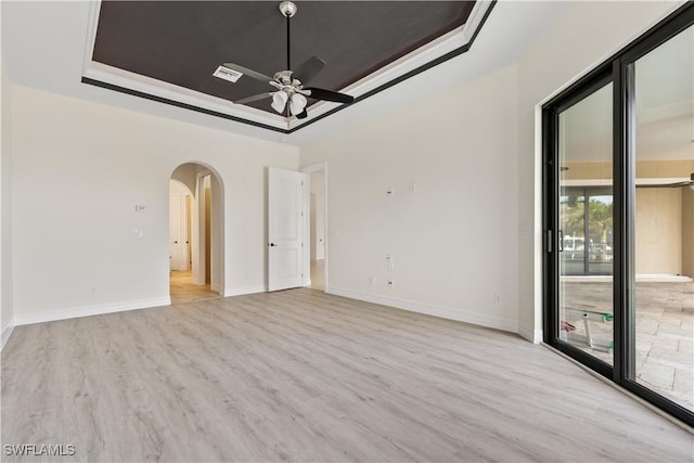 spare room with a tray ceiling, ceiling fan, light hardwood / wood-style flooring, and ornamental molding