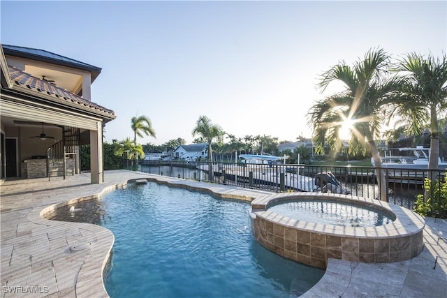 view of swimming pool with ceiling fan, a patio area, an in ground hot tub, and a water view