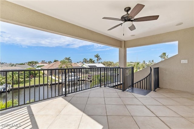 view of patio with ceiling fan, a balcony, and a water view