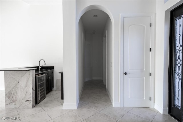 hall featuring light tile patterned floors, beverage cooler, and sink