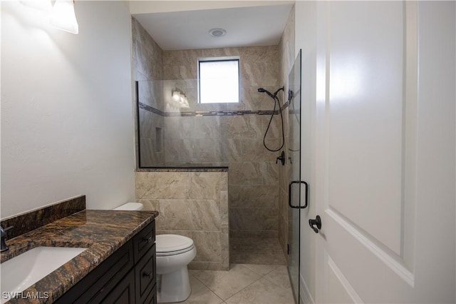 bathroom featuring tile patterned flooring, vanity, toilet, and a shower with door