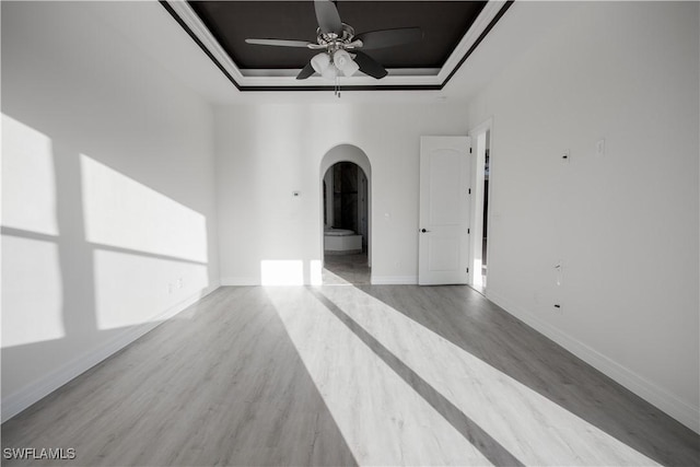 unfurnished room featuring light hardwood / wood-style floors, a raised ceiling, ceiling fan, and crown molding