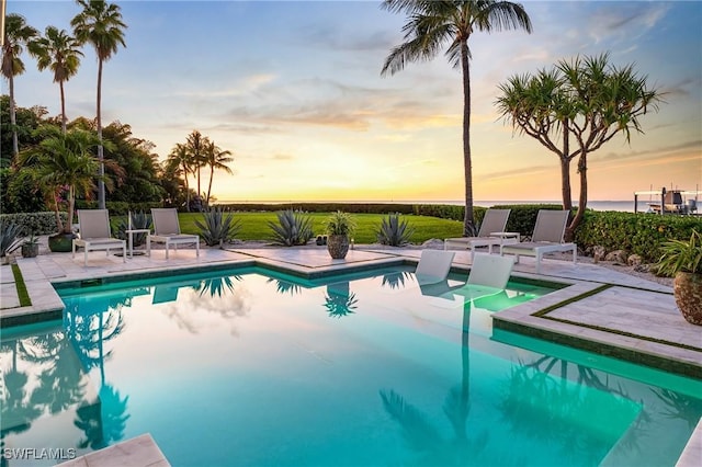 pool at dusk featuring a patio