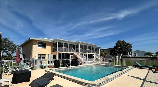 community pool with a sunroom, stairs, fence, and a patio