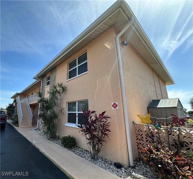 view of side of home featuring stairway and stucco siding