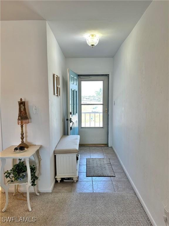 doorway featuring light carpet, baseboards, and light tile patterned floors