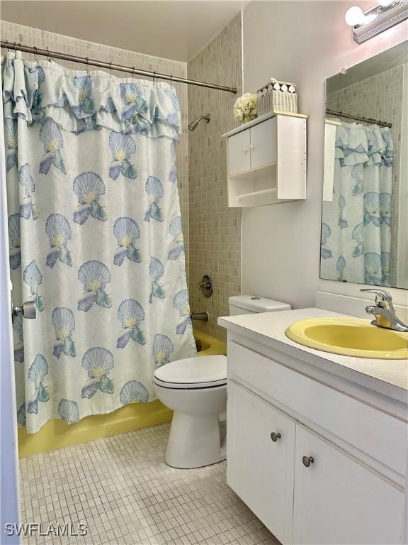 bathroom featuring tile patterned flooring, vanity, toilet, and shower / bath combo with shower curtain