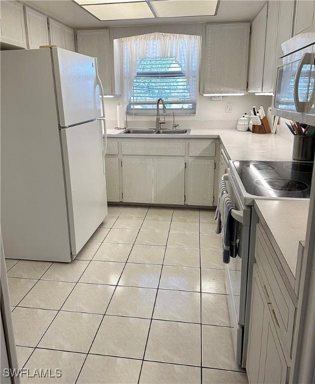 kitchen with white appliances, light countertops, a sink, and light tile patterned flooring