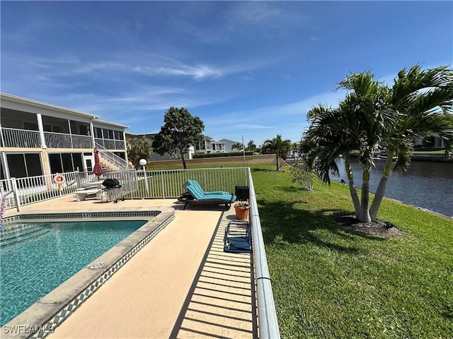 pool with a patio, a lawn, fence, and a sunroom