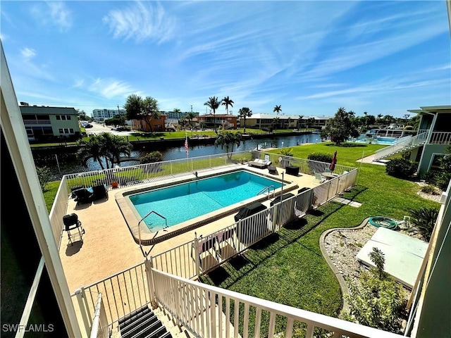 view of pool with a water view, a patio area, a lawn, and a fenced in pool