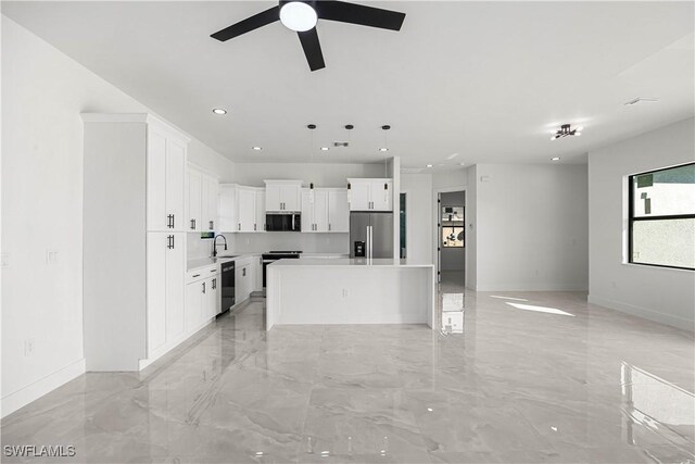 kitchen with pendant lighting, appliances with stainless steel finishes, a center island, white cabinetry, and ceiling fan