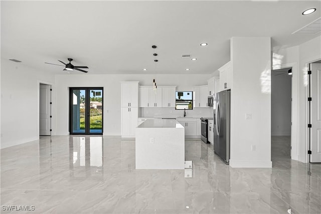 kitchen with a center island, white cabinetry, stainless steel appliances, sink, and ceiling fan