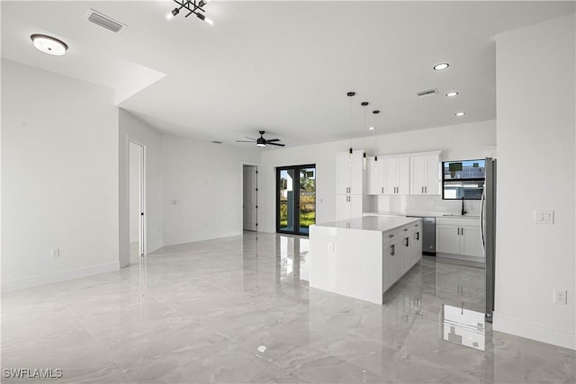 kitchen featuring ceiling fan, stainless steel appliances, decorative light fixtures, a kitchen island, and white cabinets