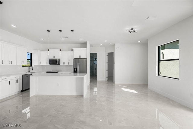 kitchen featuring a center island, sink, hanging light fixtures, stainless steel appliances, and white cabinets