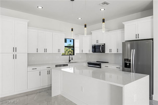 kitchen featuring pendant lighting, a kitchen island, white cabinetry, stainless steel appliances, and sink