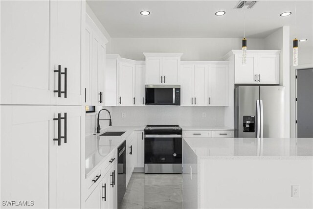 kitchen featuring appliances with stainless steel finishes, hanging light fixtures, white cabinets, light stone counters, and sink