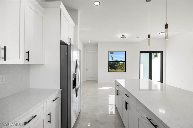 kitchen with decorative light fixtures, stainless steel refrigerator with ice dispenser, light stone countertops, and white cabinetry