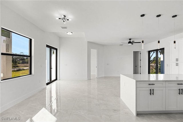 kitchen with ceiling fan, hanging light fixtures, and white cabinets