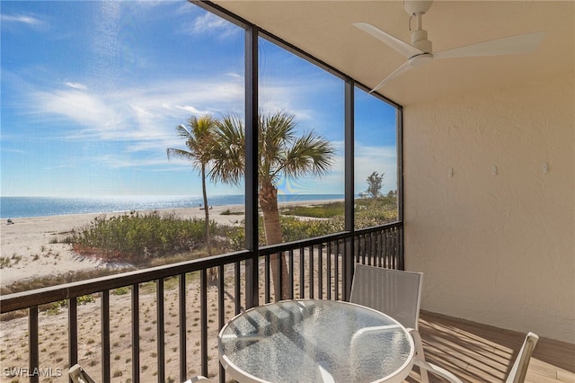 balcony with a beach view, a water view, and ceiling fan