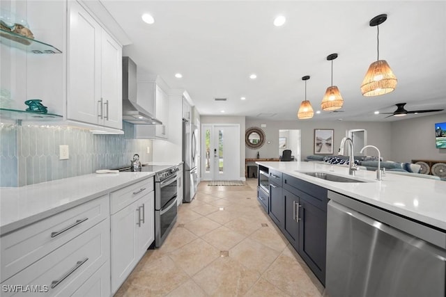 kitchen featuring wall chimney exhaust hood, appliances with stainless steel finishes, light countertops, and a sink