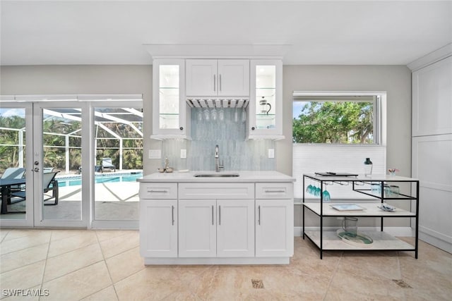 kitchen with light countertops, tasteful backsplash, a sink, and white cabinets