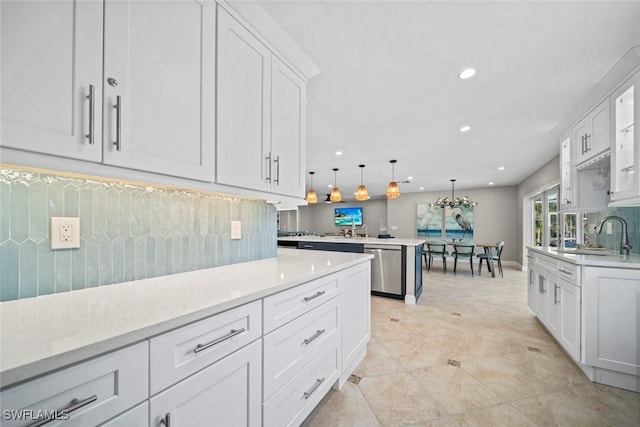 kitchen with backsplash, a peninsula, a sink, white cabinetry, and stainless steel dishwasher