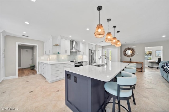 kitchen with light countertops, decorative backsplash, appliances with stainless steel finishes, a sink, and wall chimney exhaust hood