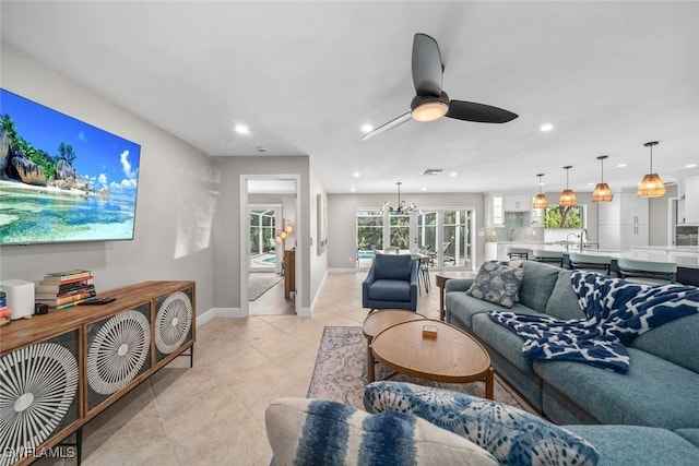 living room with recessed lighting, light tile patterned floors, baseboards, and ceiling fan with notable chandelier