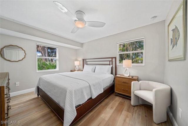 bedroom with light wood-style floors, multiple windows, baseboards, and a ceiling fan